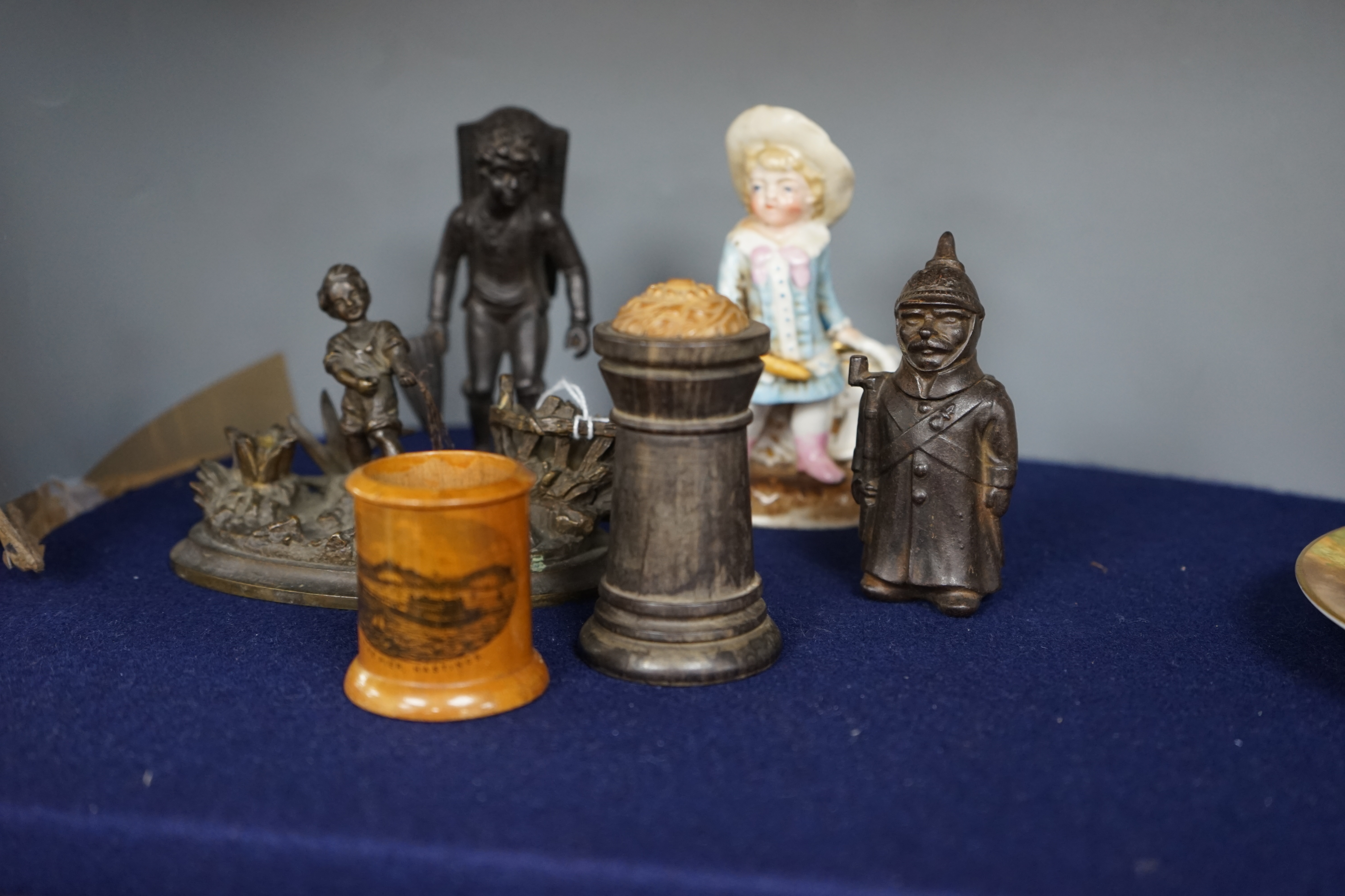 Six match tidies / strikers, including in the form of a WWI German soldier in trench coat and pickelhaube, a Mauchline ware pot with image of Hastings Pier, a cast metal figure of a boy, etc. Condition - fair